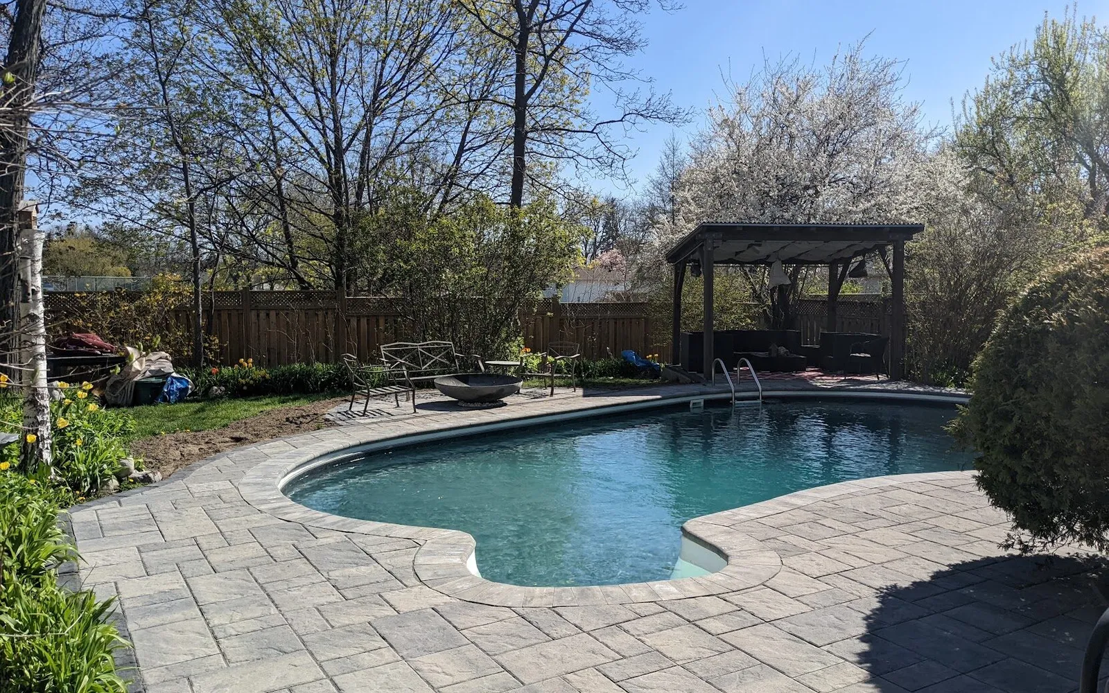 A beautiful backyard with a pool, gazebo, and firepit using a modern, but slate textured interlock