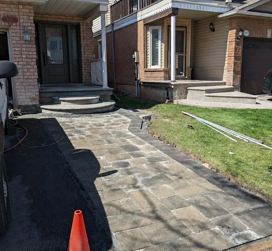 An interlock driveway/walkway extension leading to the front landing of a house