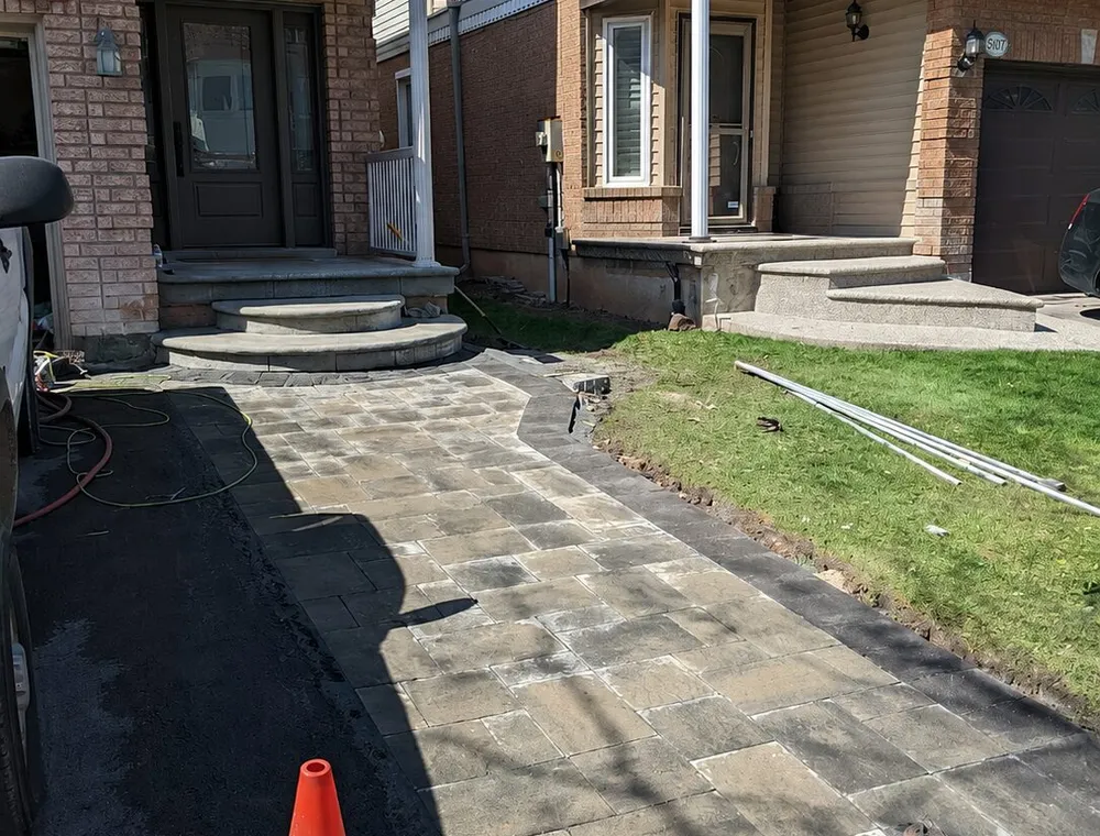 An interlock driveway/walkway extension leading to the front landing of a house