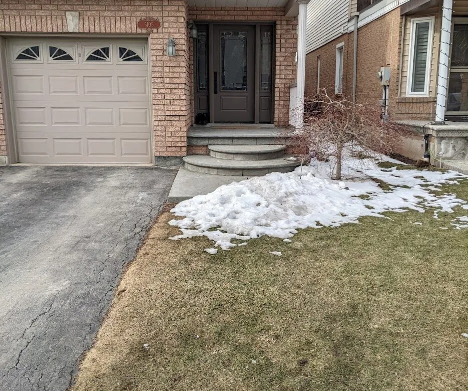 The front of a detached house with a simple poured concrete landing & step system from the driveway.
