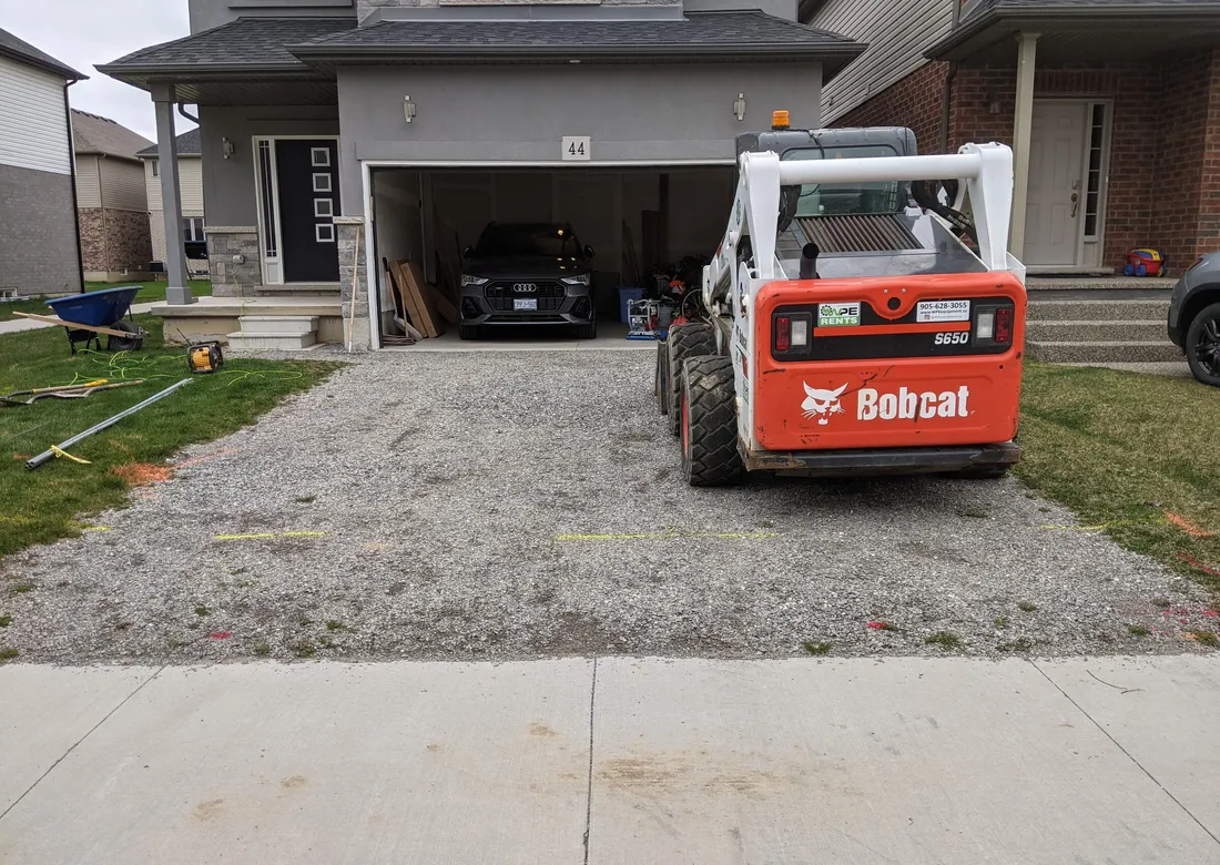 A gravel driveway with simple cast concrete steps leading to the front landing of a house