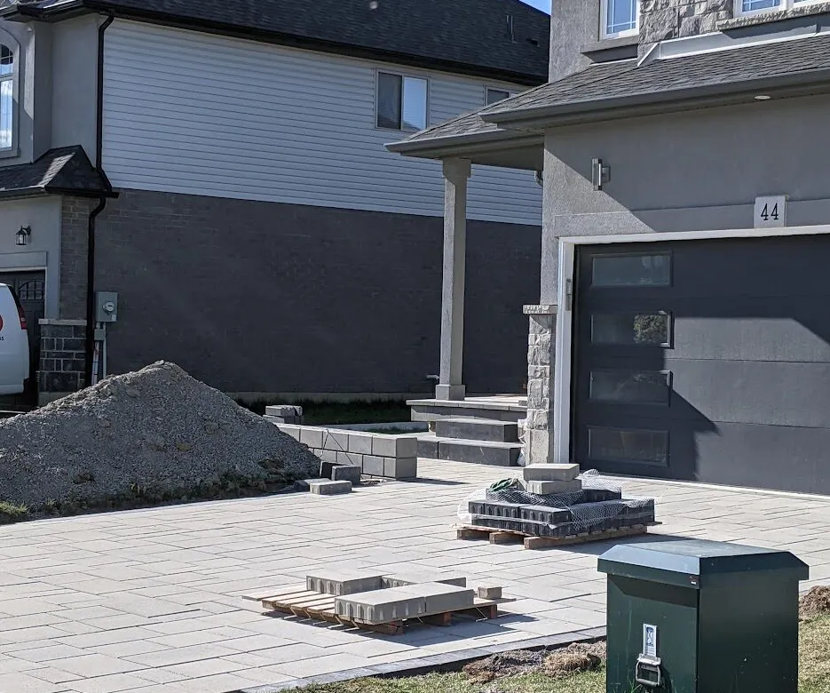 A near-complete modern driveway with some pallets of pavers sitting on top
