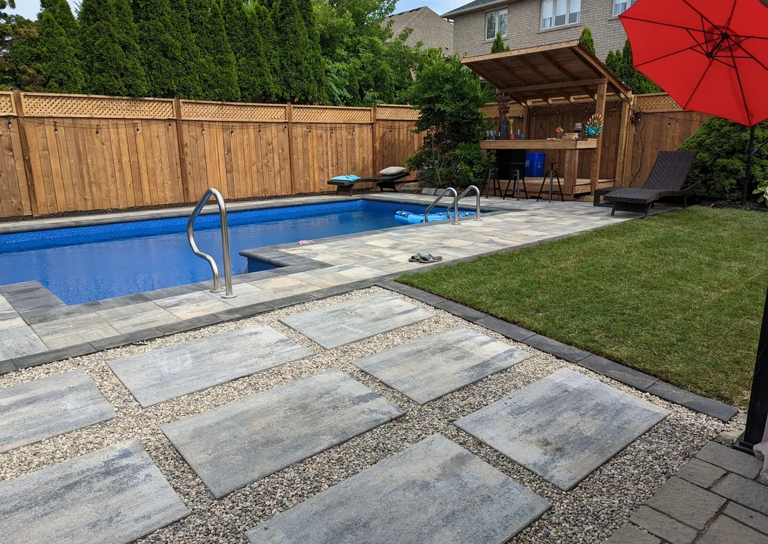 Completed pool interlock, stepping stones, river rock, and sod around the backyard pool.