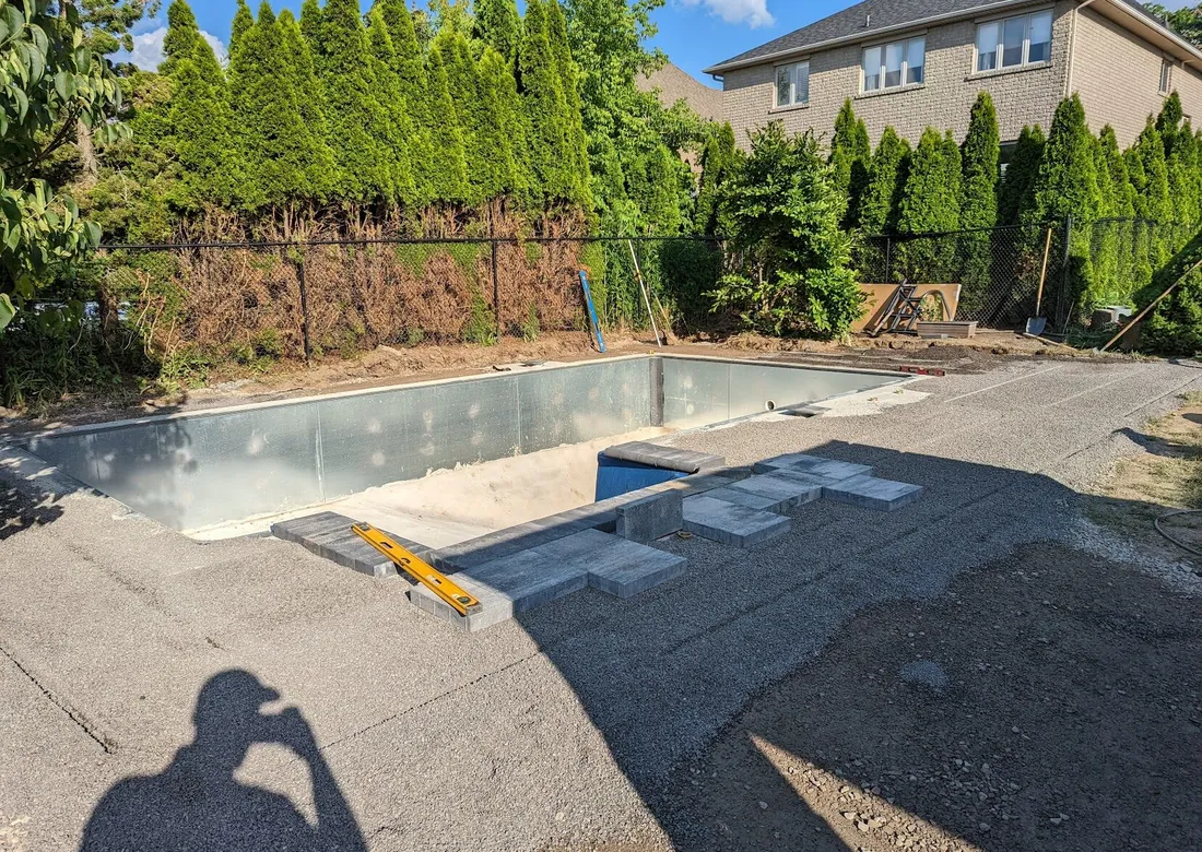 Modern slabs being installed on top of a smooth bedding, surrounding a pool