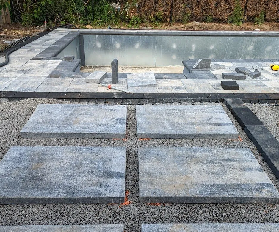 Large rectangular stepping stones laid out in 3 rows of 2 towards a swimming pool