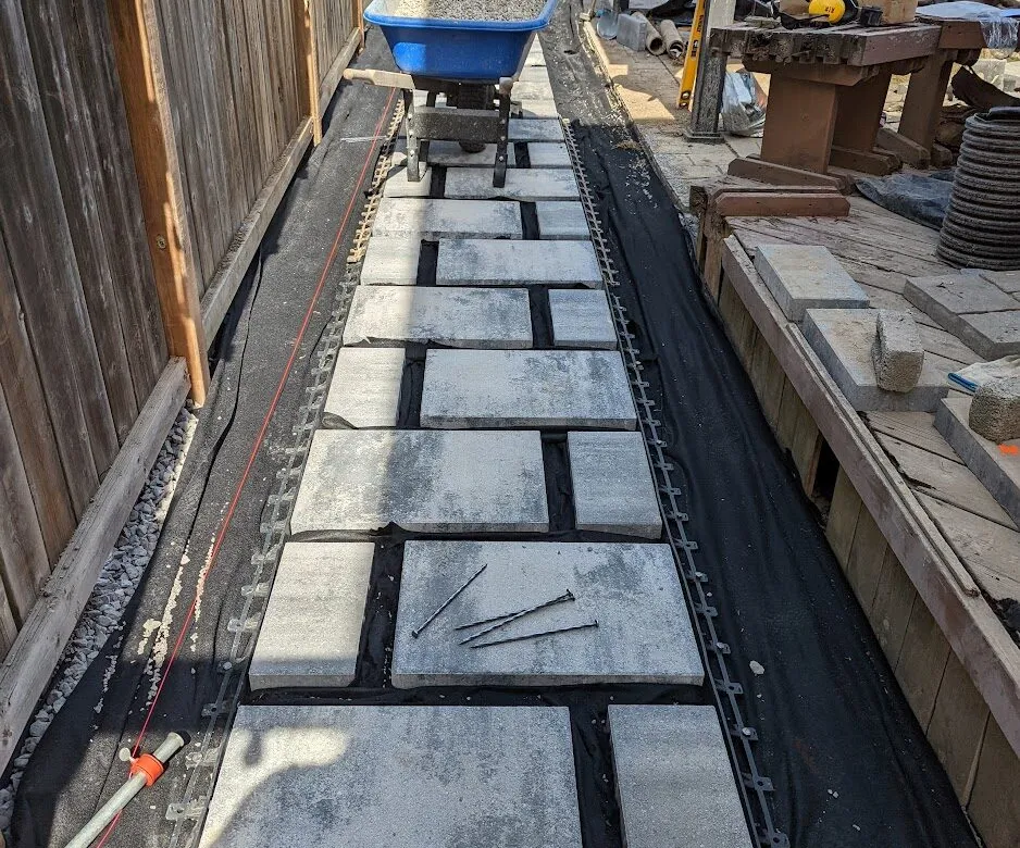 Side walkway stones installed beside the pool area for a clearer backyard route.