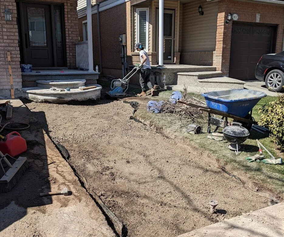 A person compacting a granular aggregate for a driveway extension