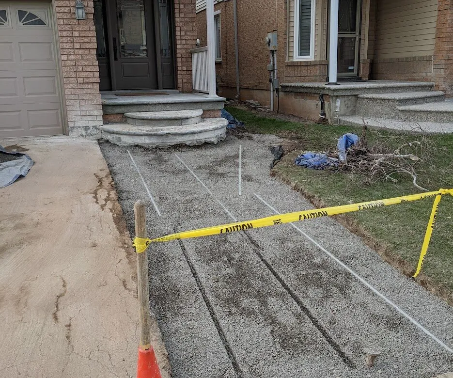 A smooth, levelled aggregate surface setting the base for a driveway extension, caution tape protects the public-facing area