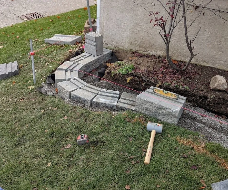 A wall from natural-faced stones being installed in a curve